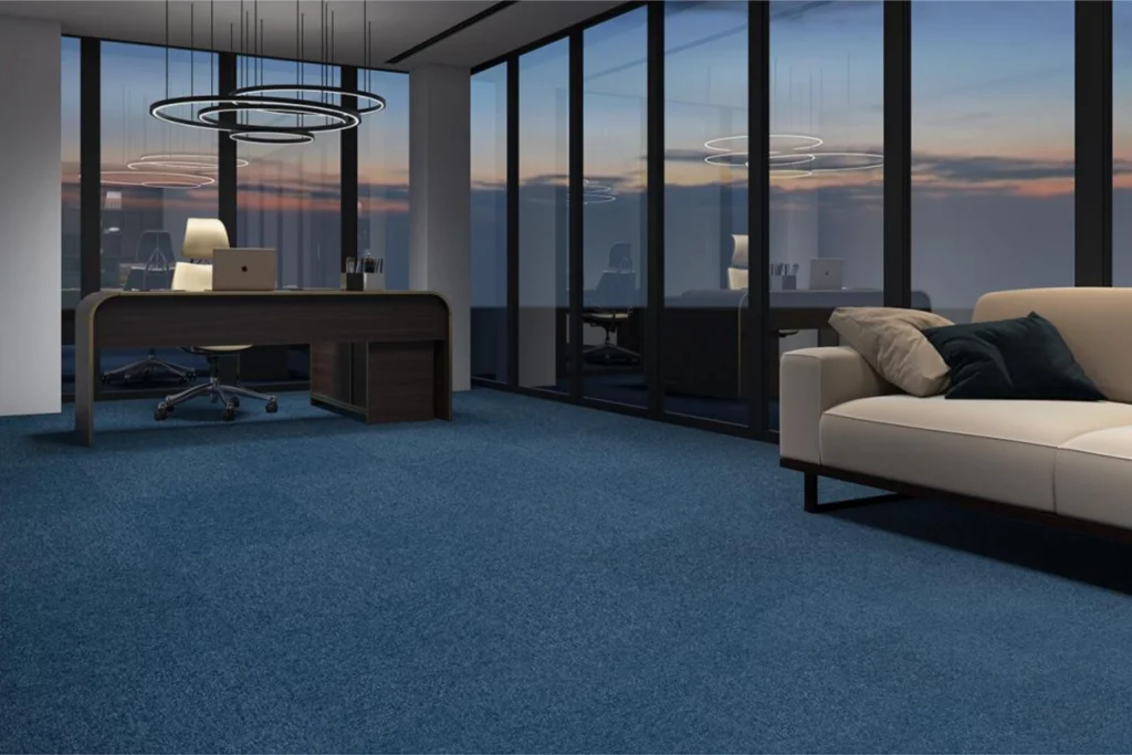 Carpete Belgotex: Modelos, Inspirações e Como escolher o ideal 1 Ambiente corporativo sofisticado com mesa de trabalho, sofá e carpete Belgotex Metrópolis azul no piso.