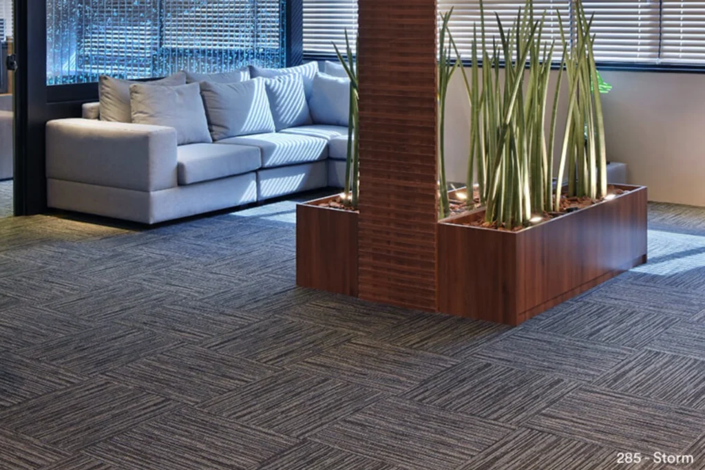 Carpete Belgotex: Modelos, Inspirações e Como escolher o ideal 6 Ambiente de recepção moderno com sofá cinza, jardim interno e carpete modular Belgotex Linea no piso.