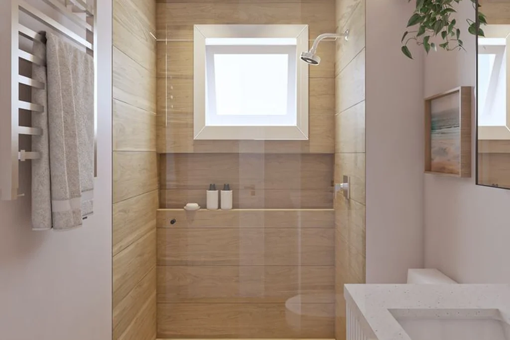 Banheiro com revestimento somente no box: 5 ideias cheias de estilo 3 Banheiro moderno com box revestido em porcelanato amadeirado, janela central, chuveiro metálico, bancada clara e piso em madeira clara.