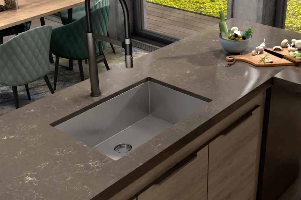 Cuba Debacco: Guia completo de modelos, Medidas e Como escolher a sua 7 Close da cuba Debacco Quadratino retangular em inox embutida na ilha, com torneira black matte e bancada marmorizada marrom ao redor.