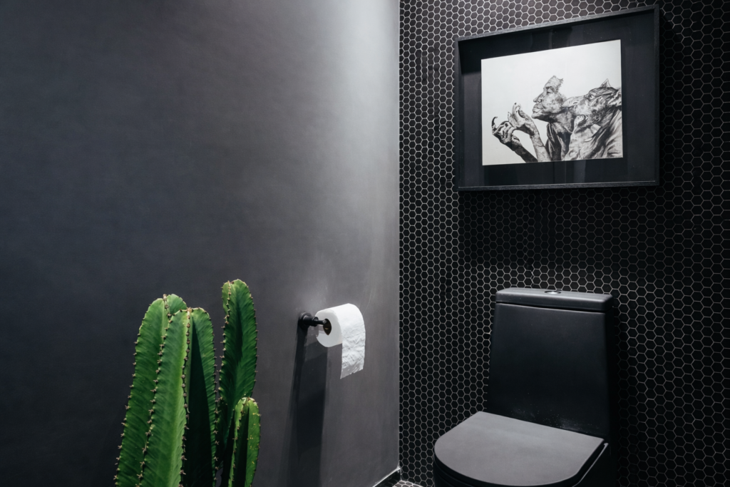 Lavabo contemporâneo com revestimento para banheiro tipo pastilha hexagonal preta, parede em tom grafite, vaso sanitário preto e decoração minimalista.